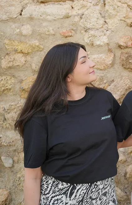 Fanus trägt ein schwarzes appsoluts-Shirt und blickt lächelnd zur Seite. Entspannter Moment während der Workation.